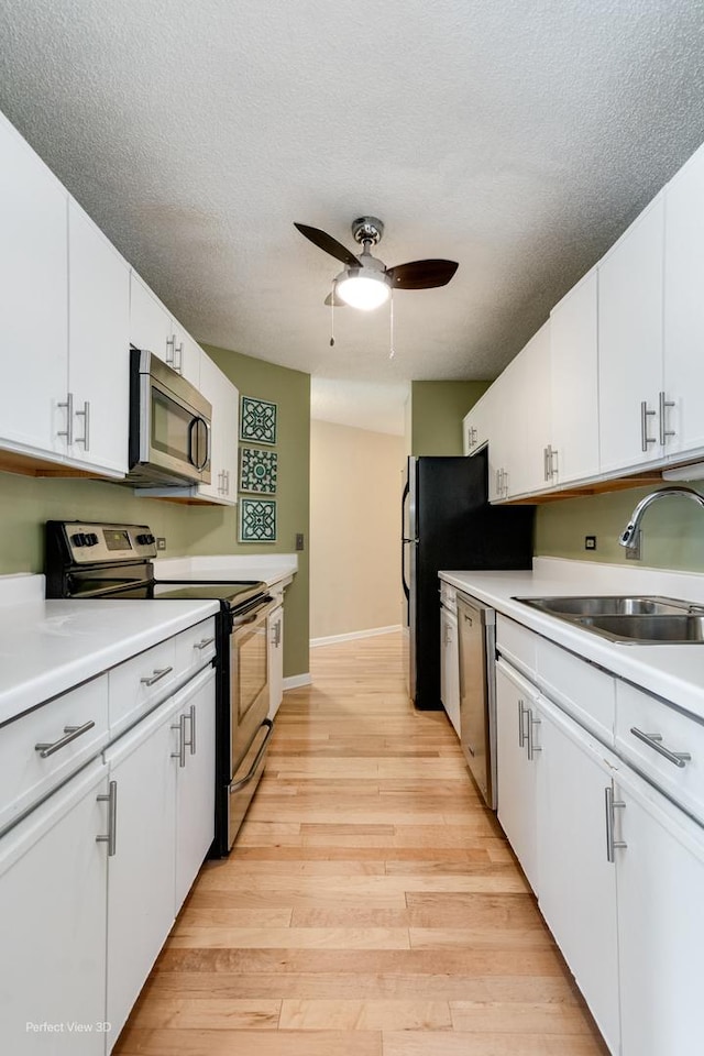 kitchen featuring sink, ceiling fan, light wood-type flooring, white cabinetry, and stainless steel appliances