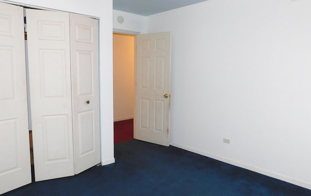 unfurnished bedroom featuring dark carpet and a closet