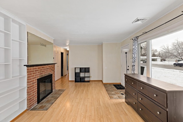 living room with a brick fireplace, ornamental molding, and light wood-type flooring