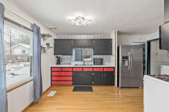 kitchen with white gas range, sink, a wealth of natural light, and stainless steel fridge with ice dispenser