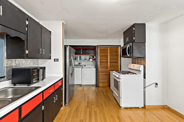 kitchen with light hardwood / wood-style floors, appliances with stainless steel finishes, decorative backsplash, and washer and dryer