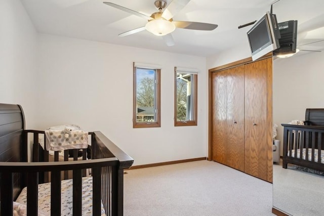 carpeted bedroom featuring ceiling fan, a closet, and a nursery area