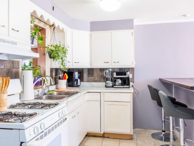 kitchen with light tile patterned floors, a sink, light countertops, under cabinet range hood, and white cabinetry