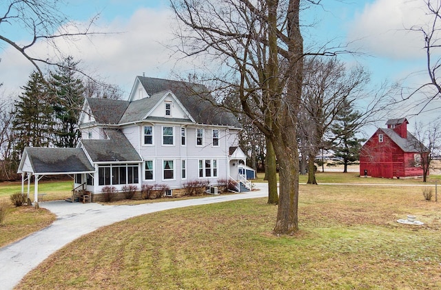 view of front of property with a sunroom, a front yard, and a carport