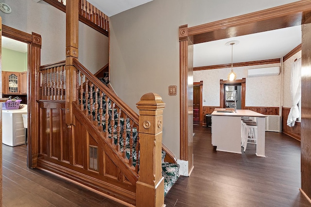 stairway with a wall mounted AC, crown molding, sink, hardwood / wood-style flooring, and washing machine and dryer