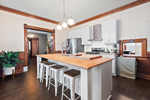 kitchen with dark hardwood / wood-style flooring, wall chimney exhaust hood, stainless steel appliances, pendant lighting, and white cabinets