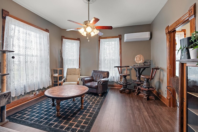 sitting room featuring dark hardwood / wood-style floors, an AC wall unit, and ceiling fan