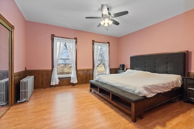 bedroom with ceiling fan, light hardwood / wood-style floors, and radiator