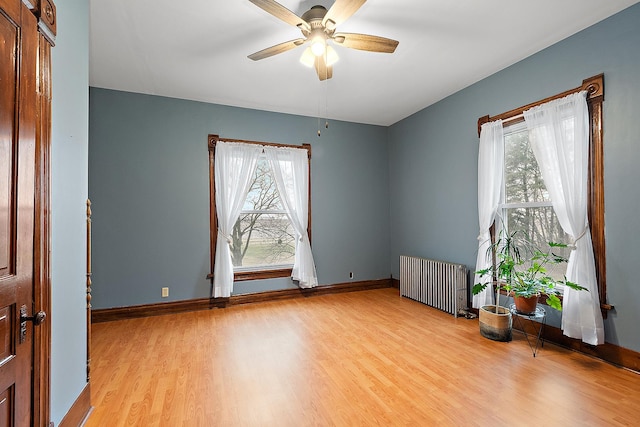 empty room featuring ceiling fan, radiator heating unit, and light hardwood / wood-style floors