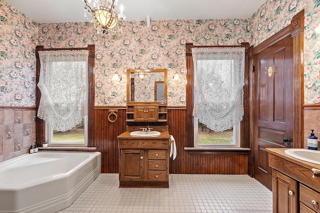 bathroom with vanity, a bath, and an inviting chandelier