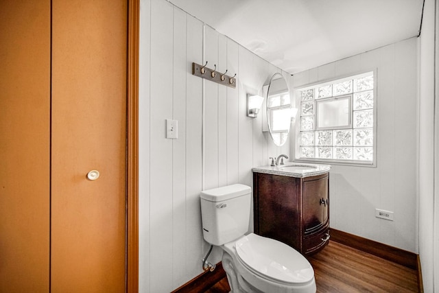 bathroom featuring vanity, wood walls, toilet, and wood-type flooring