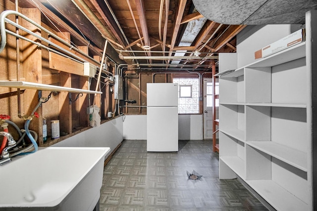 basement with white refrigerator and sink