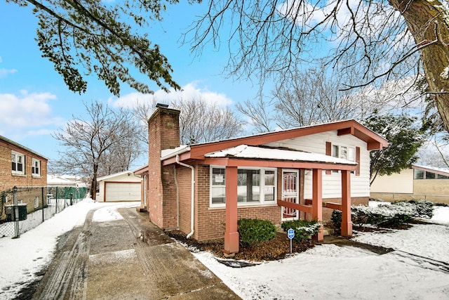 view of snowy exterior with an outbuilding and a garage