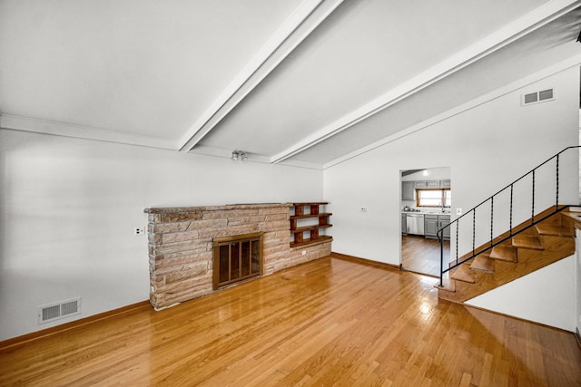 living room featuring a fireplace, vaulted ceiling with beams, and hardwood / wood-style flooring