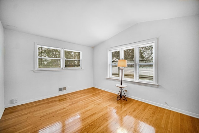 unfurnished room featuring hardwood / wood-style flooring and lofted ceiling