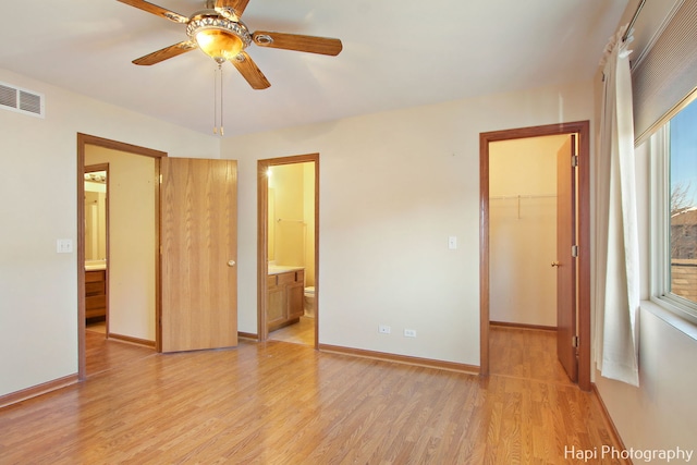 unfurnished bedroom featuring ensuite bath, ceiling fan, a spacious closet, light hardwood / wood-style floors, and a closet