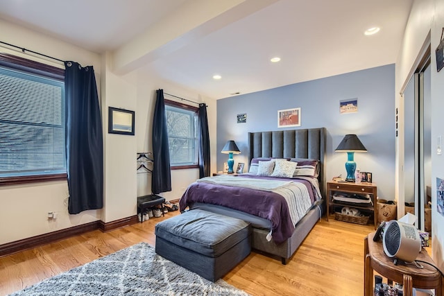 bedroom with beamed ceiling and light hardwood / wood-style floors