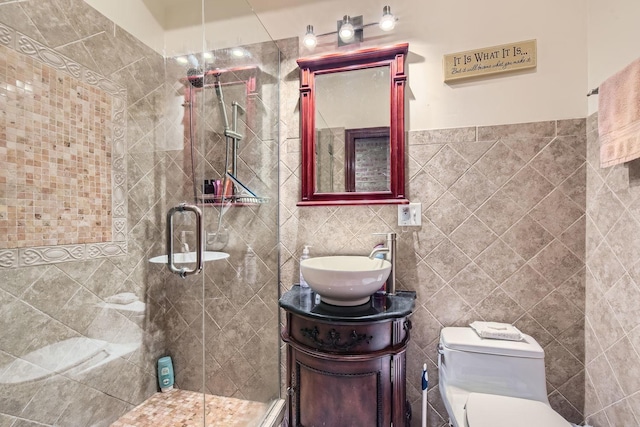 bathroom with an enclosed shower, vanity, toilet, and tile walls