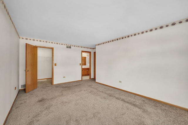 unfurnished bedroom with carpet, a walk in closet, and a closet