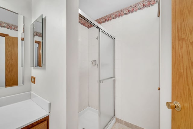 bathroom featuring a shower with door and vanity