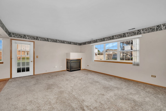 unfurnished living room with carpet flooring and plenty of natural light