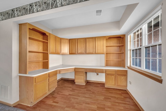 unfurnished office featuring built in desk and light wood-type flooring