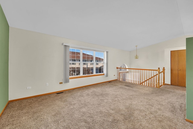 carpeted spare room featuring vaulted ceiling