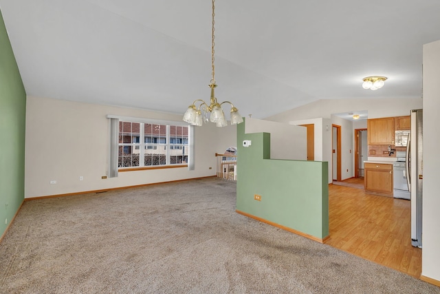 unfurnished dining area featuring an inviting chandelier, light hardwood / wood-style flooring, and vaulted ceiling