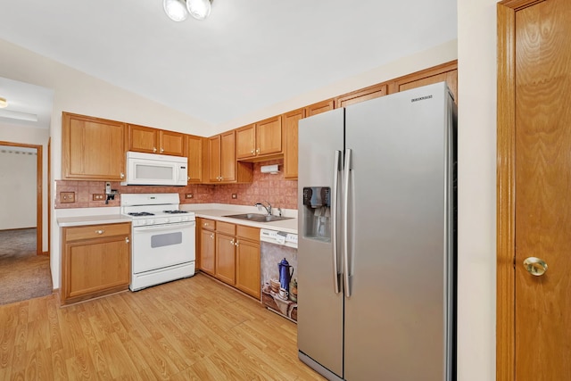 kitchen with white appliances, backsplash, sink, light hardwood / wood-style flooring, and vaulted ceiling