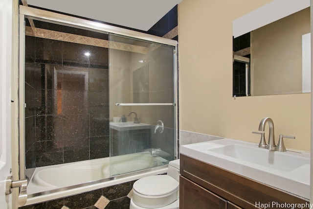 full bathroom featuring vanity, bath / shower combo with glass door, and toilet