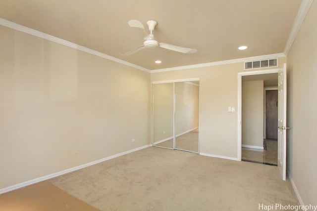 unfurnished bedroom with light carpet, a closet, ceiling fan, and crown molding