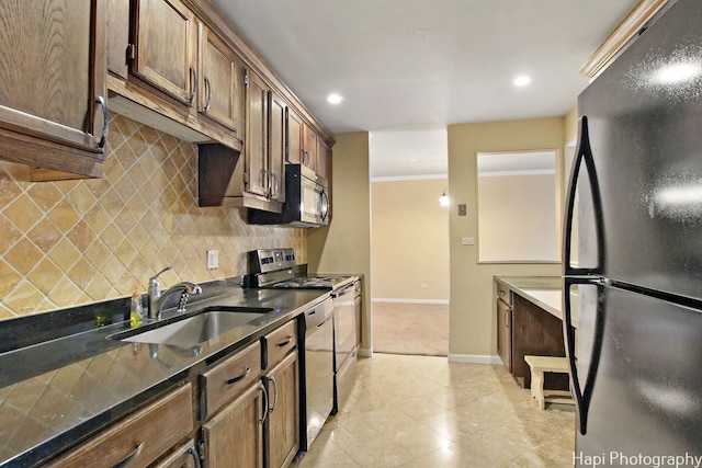 kitchen with dark stone counters, sink, ornamental molding, appliances with stainless steel finishes, and tasteful backsplash