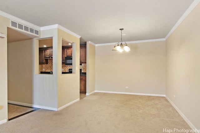 carpeted empty room featuring crown molding and a chandelier