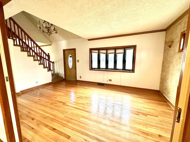 foyer featuring crown molding, light hardwood / wood-style floors, a textured ceiling, and a notable chandelier