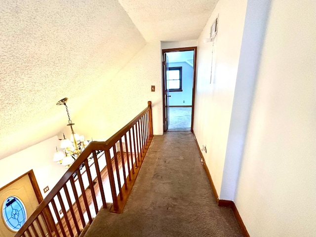 hall featuring a textured ceiling, vaulted ceiling, and dark carpet