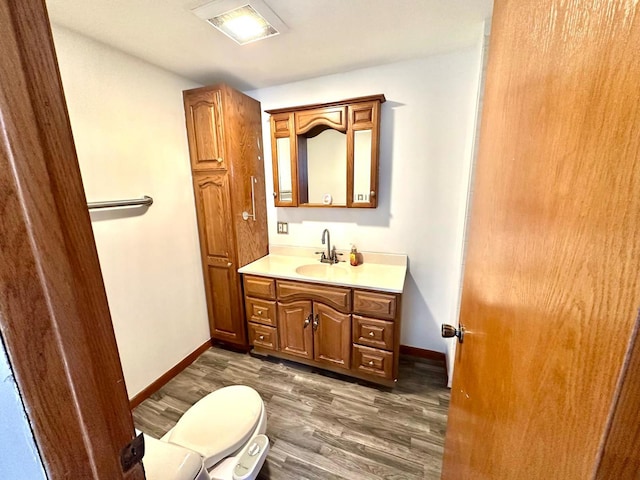 bathroom with hardwood / wood-style flooring, toilet, and vanity