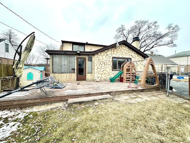 back of property featuring a sunroom, a wooden deck, and a playground