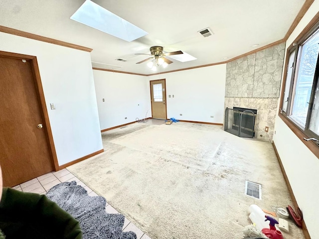 carpeted living room featuring ceiling fan, crown molding, a skylight, and a fireplace