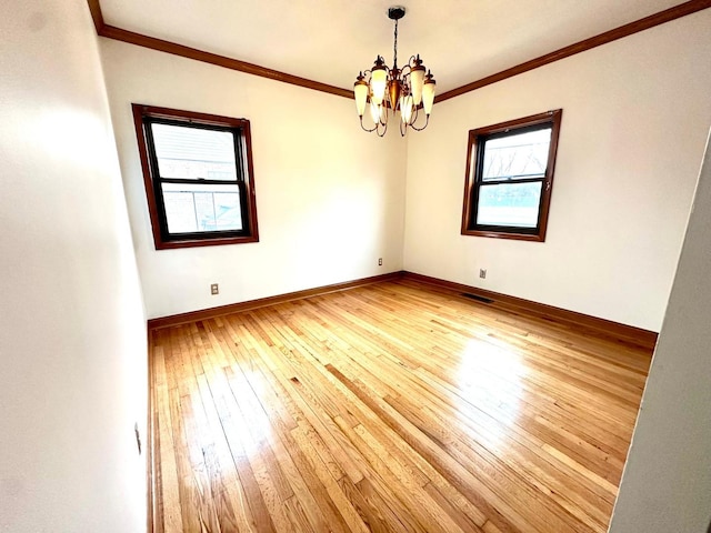 spare room featuring hardwood / wood-style flooring, a chandelier, and ornamental molding