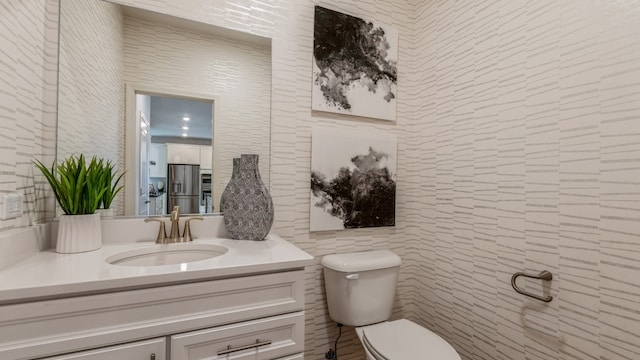 bathroom featuring vanity, tile walls, and toilet