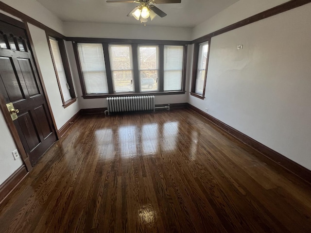 empty room featuring ceiling fan, radiator heating unit, and dark wood-type flooring