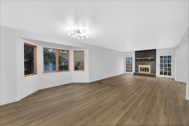 unfurnished living room with a fireplace, dark hardwood / wood-style floors, and an inviting chandelier