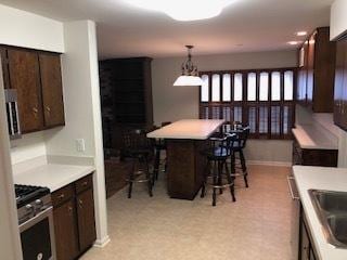 kitchen with a kitchen breakfast bar, dark brown cabinetry, high end stove, and pendant lighting