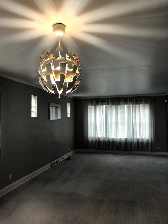 spare room featuring carpet floors, ornamental molding, and a notable chandelier