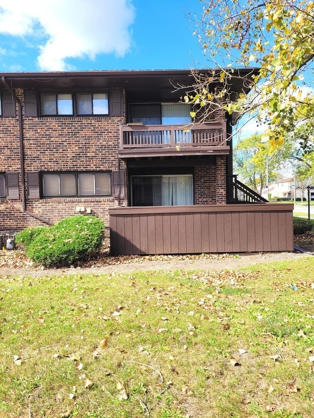 back of house with a balcony and a lawn