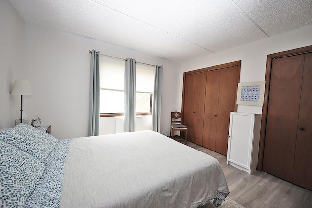 bedroom featuring light hardwood / wood-style flooring and multiple closets