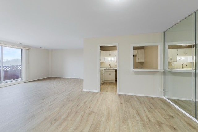 unfurnished living room featuring sink and light hardwood / wood-style floors