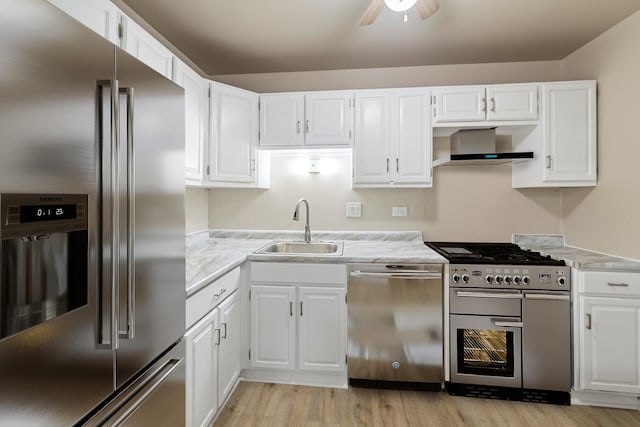 kitchen featuring wall chimney exhaust hood, sink, light hardwood / wood-style flooring, high quality appliances, and white cabinets