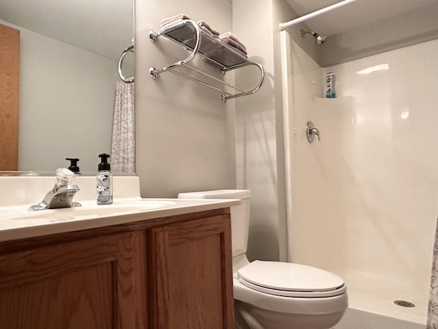 bathroom with a shower, vanity, and toilet