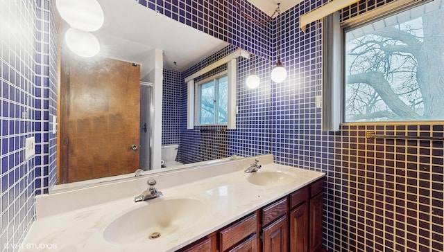 bathroom with tile walls, vanity, and toilet